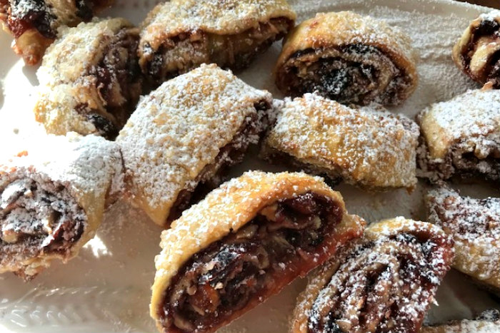 Close up of a half dozen roly poly pastries topped with powdered sugar