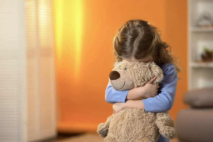 Child with her face covered by a teddy bear