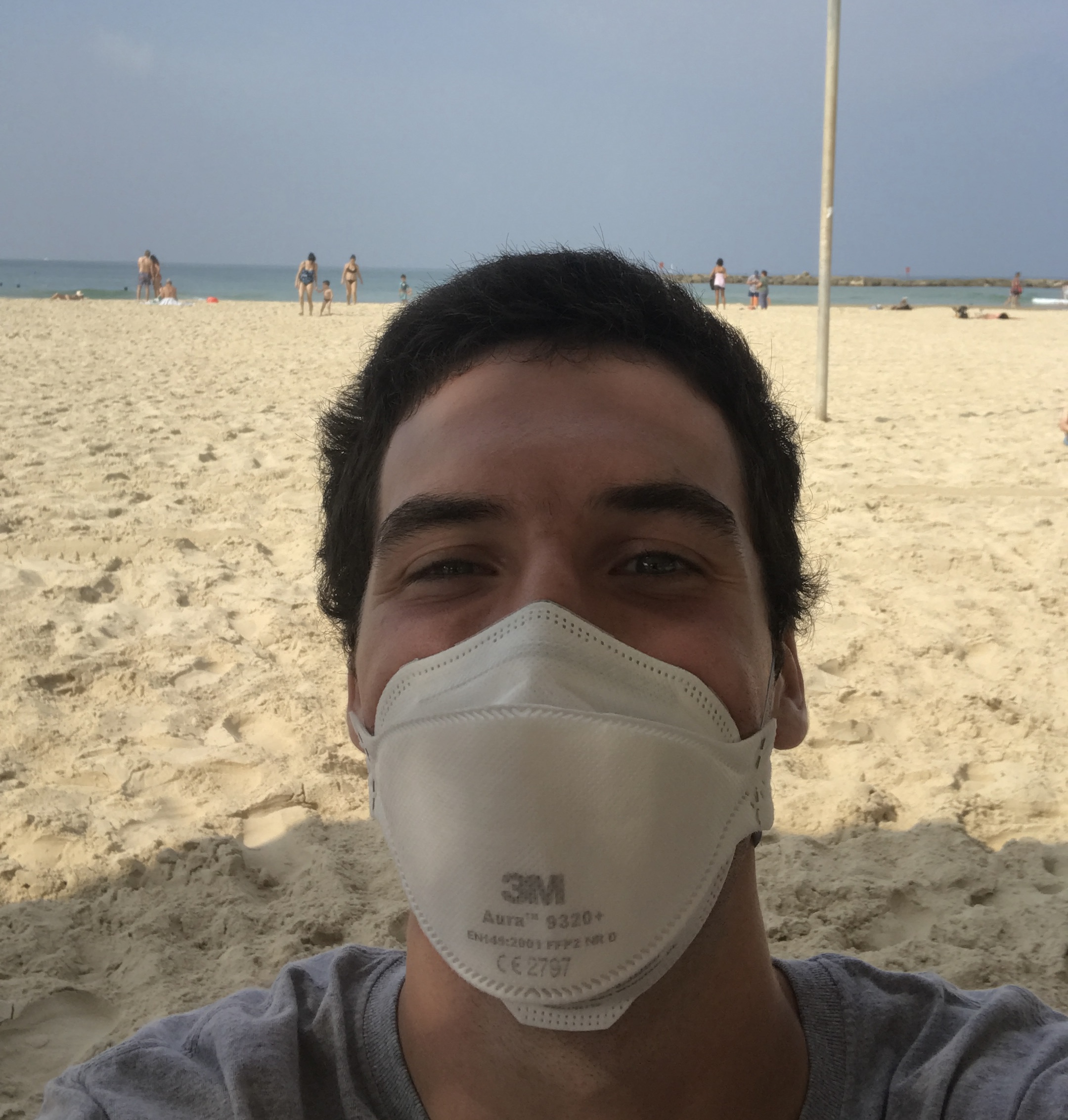 Selfie of Josh Glucksman wearing a face mask on a beach