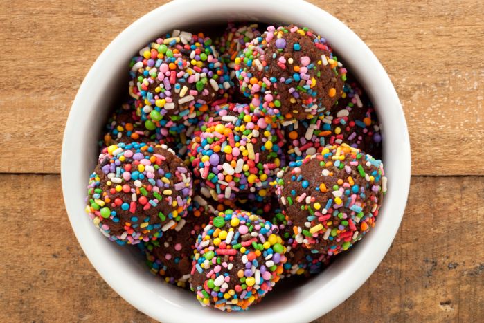White bowl filled with small chocolate balls covered in sprinkles