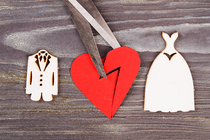an image of a tuxido and a wedding dress, with a red heart in the middle, and scissors cutting the heart in half