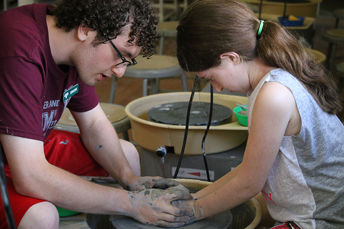 a young girl and male counselor doing pottery at camp