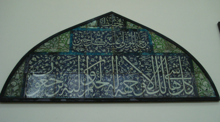 Framed artwork that includes Arabic writing on a background of blue, black, and green
