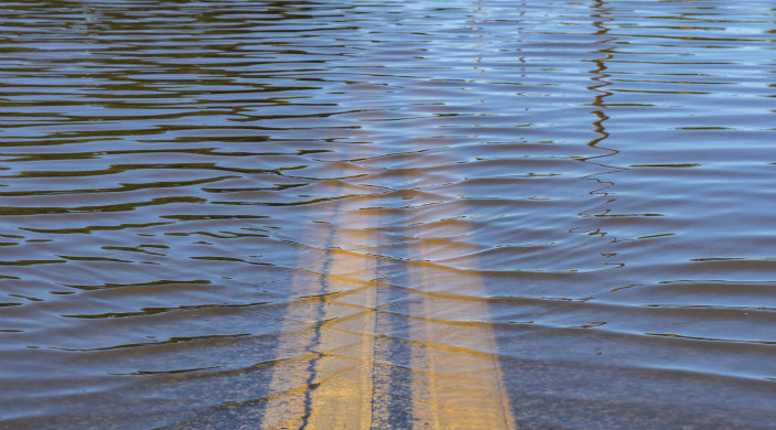 Flooded street with the painted yellow lines visible beneath flood waters