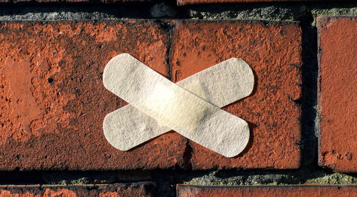Two crossed Bandaids over a patch of brick wall