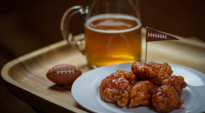 Plate of chicken wings next to a beer glass and a small plastic football