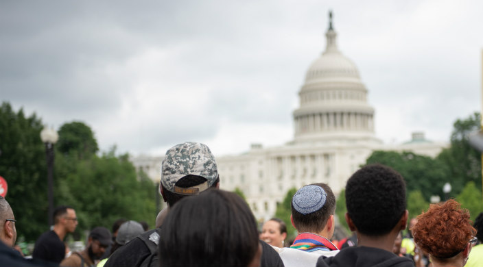 Black and white people standing with their back to the camera facing the US Capitol building