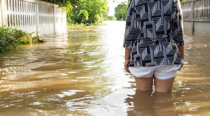 See from behind: woman in shorts standing in thigh-high flood water