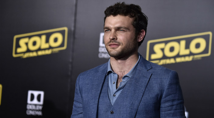 Alden Ehrenreich standing in front of a step-and-repeat board with the “Solo: A Star Wars Story” logo on it