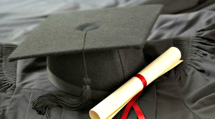 Graduation cap and diploma atop a graduation gown