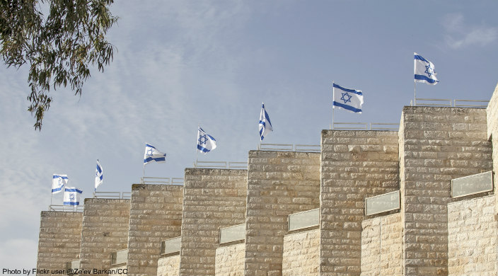 Jerusalem stone columns, each topped by a waving Israeli flag
