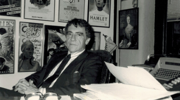 Black and white image of Joe Papp sitting behind a desk 
