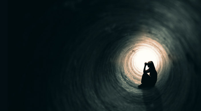 Silhouette of a woman sitting in a tunnel as if to represent social isolation