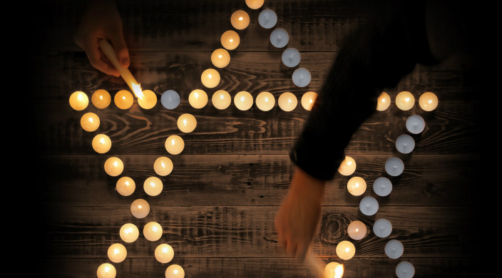 Tealights in the shape of a Star of David with hands reaching in to light some of the candles