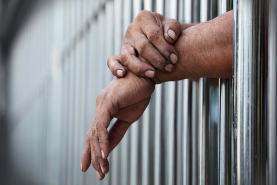 Prisoner's hands and arms coming through jail cell bars
