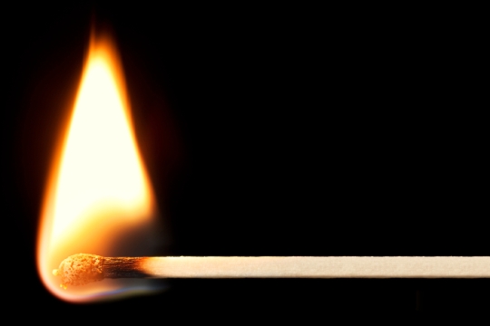 Closeup of a burning match against a black background