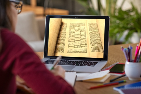 Student taking a Judaism class online and looking at image of Torah on computer 