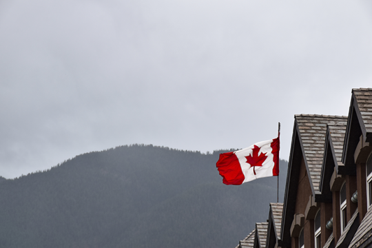 canadian-flag-on-top-of-building-with-mountain