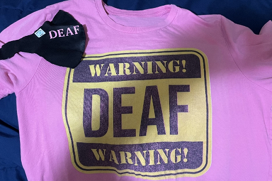 A pink t-shirt that reads "Warning! Deaf Warning!