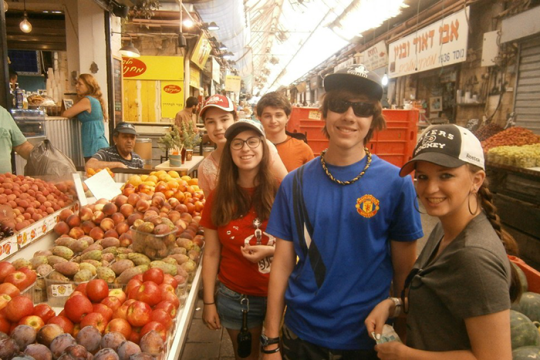 an image of 5 kids standing by a fruit stand in a market in Israel