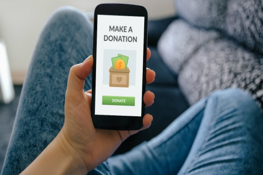 Hand holding a smartphone with a large DONATE button