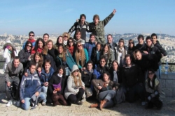 Group of smiling young adults on an overlook in Israel with the Jerusalem skyline behind them