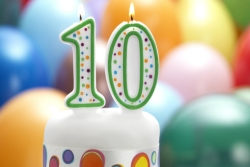 Colorful candles shaped like the number 10 lit atop a birthday cake 