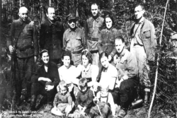 Jewish Holocaust era rescuer Tuvia Bielski and a group of other Jews standing in the woods in an old black and white photo from the Yad Vashem Photo Archives
