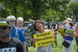 Woman carrying sign that reads "Ecological Devastation is Immoral"