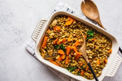 White casserole pan full of curried lentils with carrots and mushrooms 