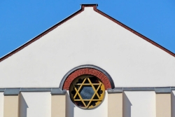 Outside of a white synagogue building with a Star of David stained glass window