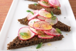 Thinly sliced radishes with olive oil and greens atop triangles of rye bread 