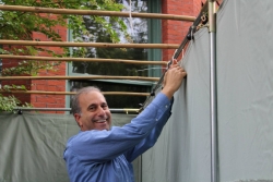 Smiling man tying the sides onto a sukkah 