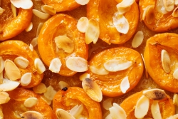 Closeup of baked apricots sprinkled with sliced almonds
