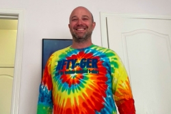 The author smiles while wearing a long sleeved tie dyed shirt that says NFTY GER across the front