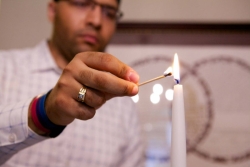 Closeup of a young man lighting Shabbat candles