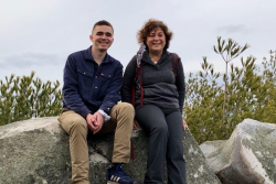 The author sitting on a mountain rock next to the young man who rescued her