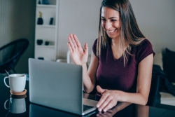 Woman waving at a laptop screen