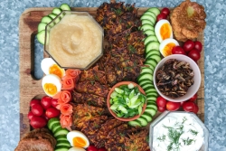 Latke board featuring two kinds of latkes with sour cream applesauce and other toppings