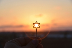 Small Star of David held up against a sunset