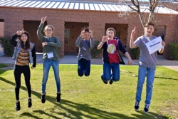 Five smiling teenagers jumping in unison