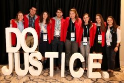 Group of teens in red vests in front of 3D block letters reading DO JUSTICE