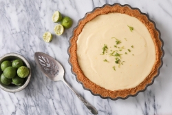 Aerial image of key lime pie on a marble countertop next to cut limes 