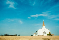 Small white church against a blue sky in a rural area