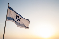 Israeli flag waving against a sunset