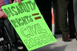 Person in a wheelchair holding a sign that says "disability rights=civil rights"