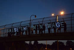 Raise the Wage sign on a bridge