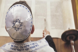 View of a boys head from above as he reads Torah using a yad 
