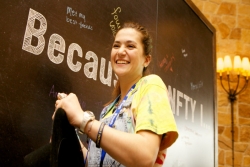 Smiling teen girl in front of a chalkboard that reads BECAUSE OF NFTY I...