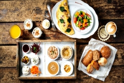 Aerial view of a large spread of Israeli food from Cafe Landwer on a wooden table